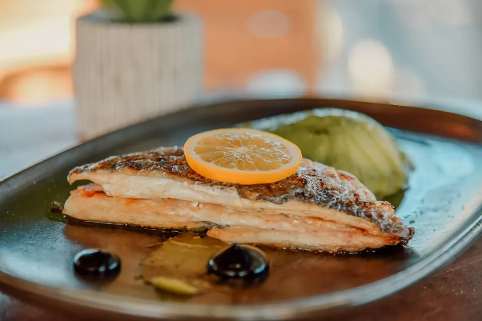 Seared fish fillet with citrus on a deep blue glazed plate