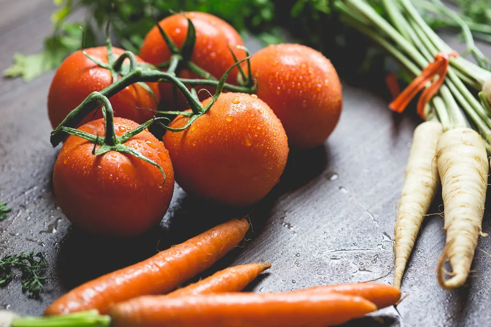 Vine tomatoes, carrots and radish on a dark wooden surface