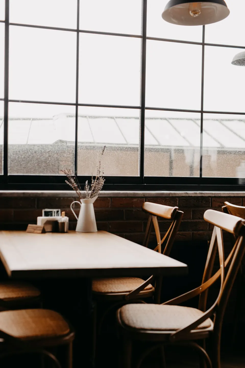 Bentwood chairs and a set table beside tall restaurant windows